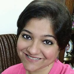 Aditi Malhotra headshot photo, smiling woman with dark hair wearing a pink top