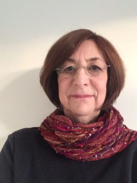 Barbara Smith PCC headshot photo, smiling woman wearing glasses a red scarf and a black top in front of white wall