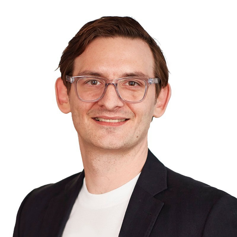 Headshot of a man wearing glasses in front of a white backdrop