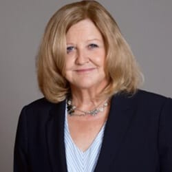 Kelly Gallagher PCC headshot photo, smiling woman with blond hair wearing a black blazer and light top in front of gray background