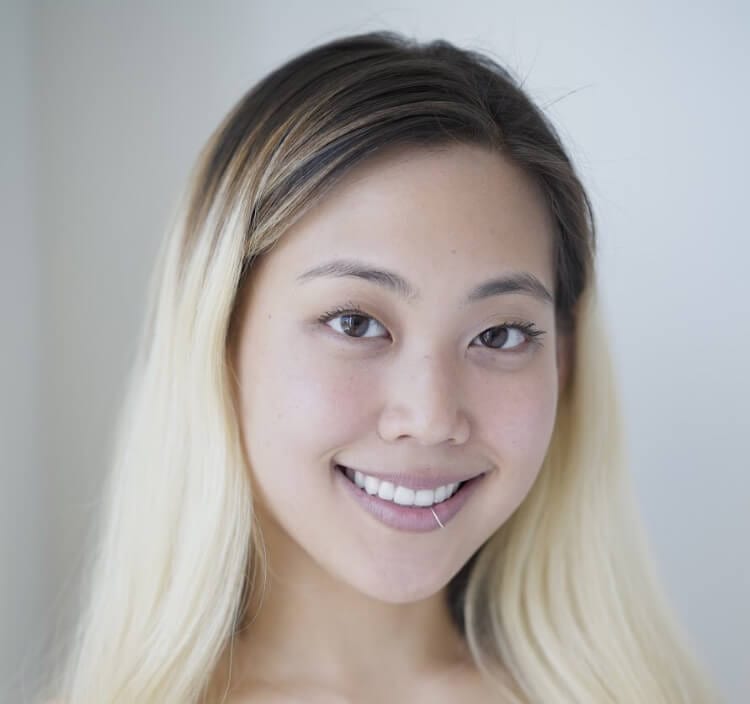Christen Lee headshot photo, smiling blond woman in front of light gray background