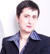 Maite Baron headshot photo, woman with short dark hair wearing blazer in front of white wall