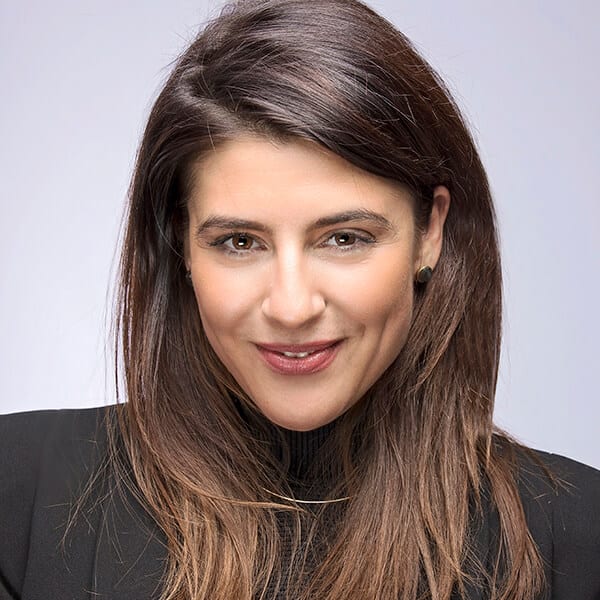 Marina Cvetkovic headshot photo, smiling woman with dark hair wearing a dark blazer in front of light background