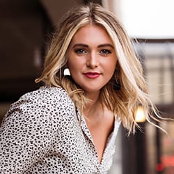Morgan Dubbels headshot photo, smiling blond woman with printed top outside