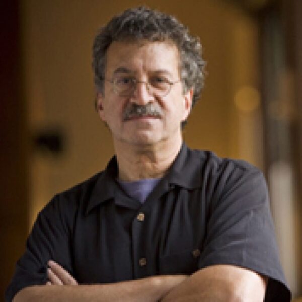 Dr. Robert Kegan headshot photo, man wearing black collared shirt with arms crossed over his chest in front of neutral background