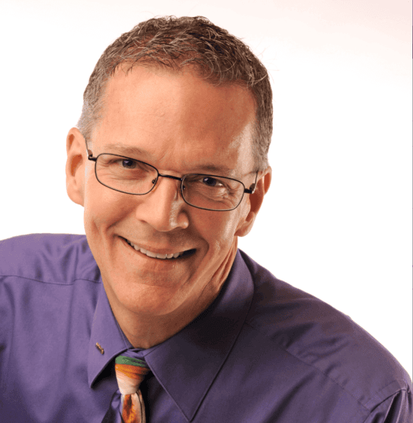 Jim Smith PCC headshot photo, smiling man wearing purple collared shirt and multicolored tie in front of white background