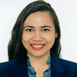 Feb Paquera headshot photo, smiling woman with dark hair wearing a dark blazer and top in front of a white background