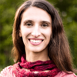 Vanessa Osage headshot photo, smiling woman with brown hair and pinkish red top and scarf outside