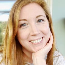 Verity Symcox headshot photo, smiling woman with blond hair and hand on chin