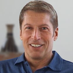 Garry Schleifer PCC headshot photo, smiling man with blond hair wearing blue collared shirt