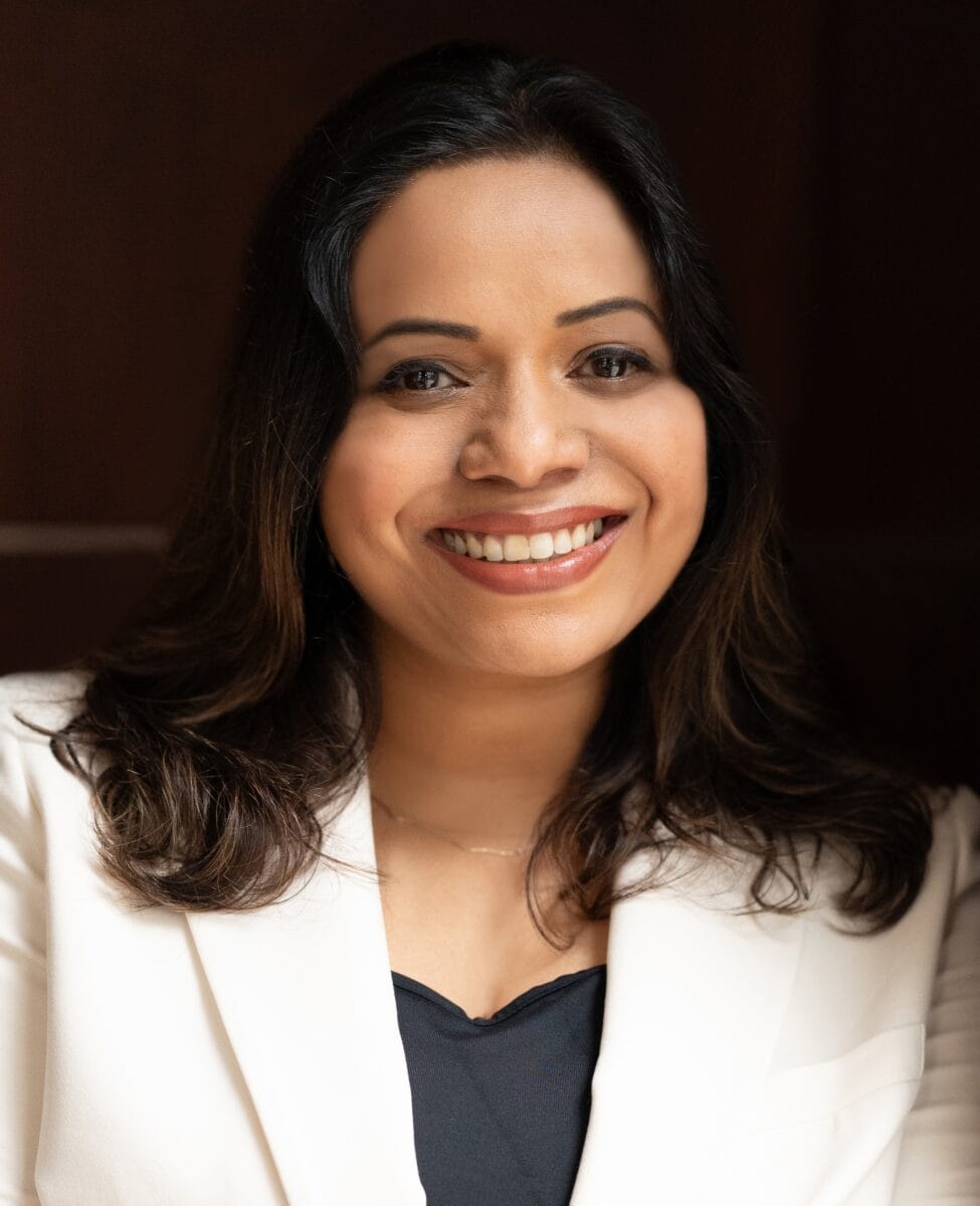 Rachel Gojer MCC ACTC BE ITCA headshot photo, woman with dark hair against black background smiling