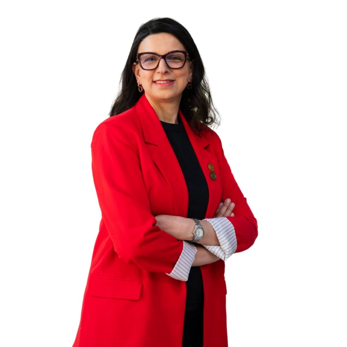 Jihane Labib headshot photo, smiling woman wearing pink top with hands clasped on her knee sitting in front of light background