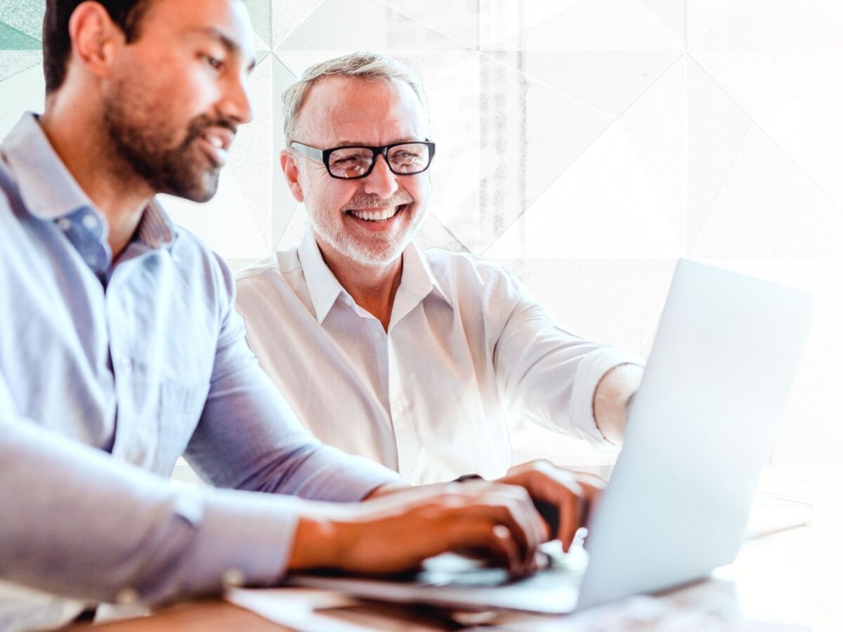 Two men read the ICF Code of Ethics through a laptop.