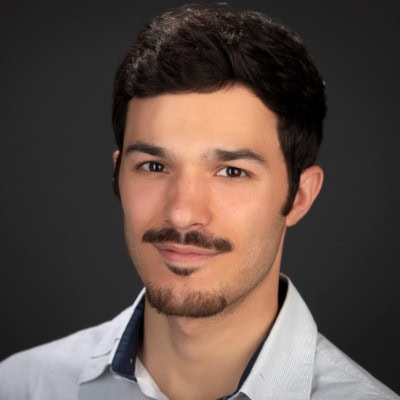 Headshot of a man with black hair standing in front of black backdrop
