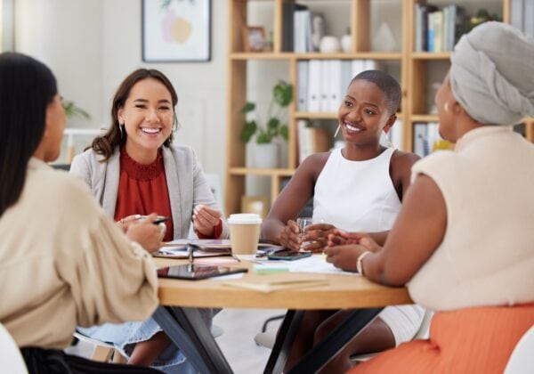 Four professionals smiling and collaborating at a business meeting.