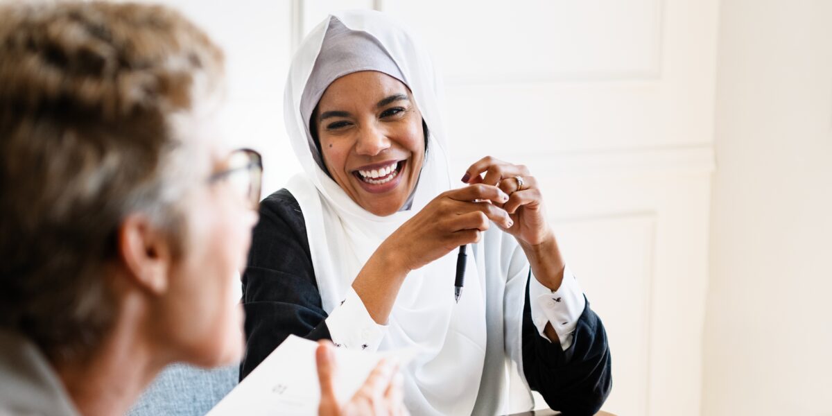 A woman wearing a hijab talking with another woman about ICF Credentials