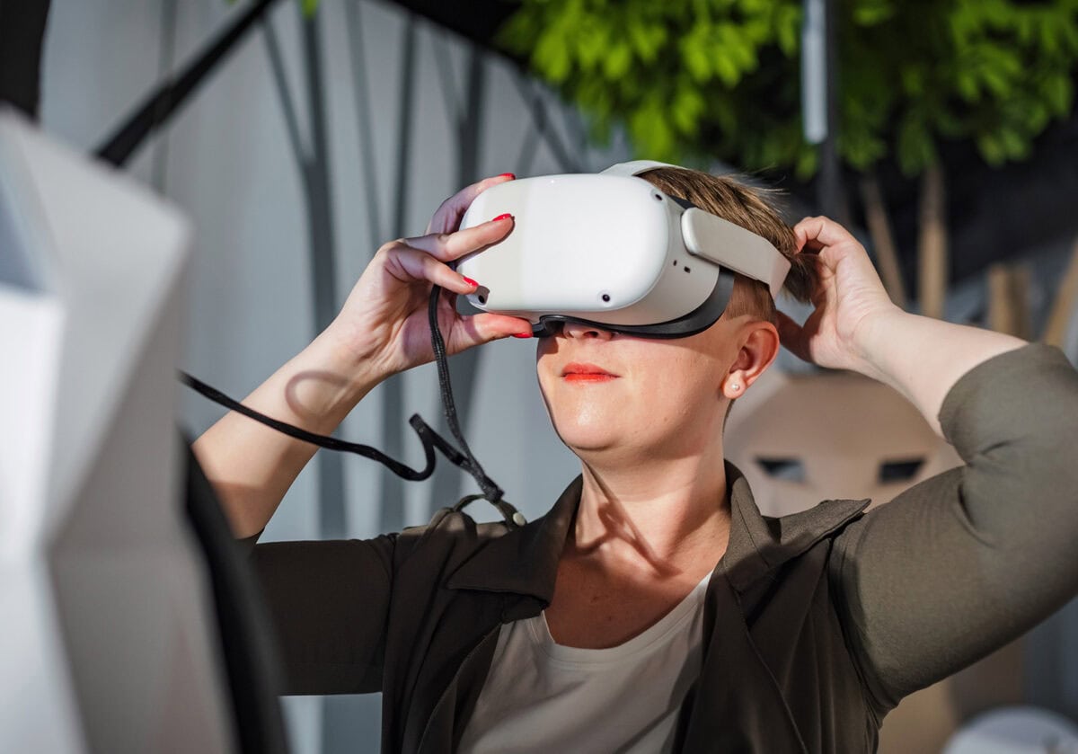 Woman using a virtual reality headset to explore immersive coaching technology.