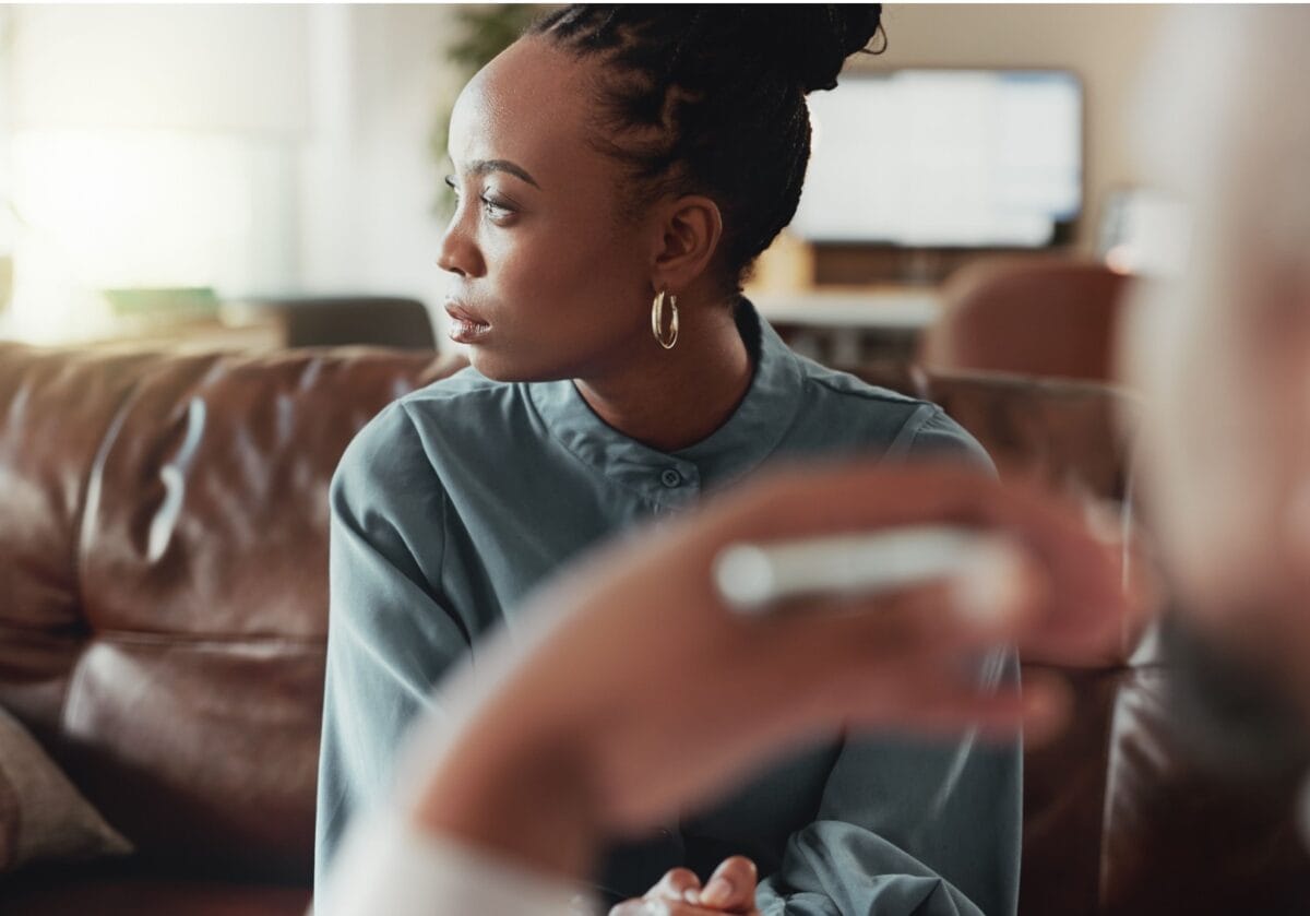 A pensive woman looking away thoughtfully during a grief coaching session.