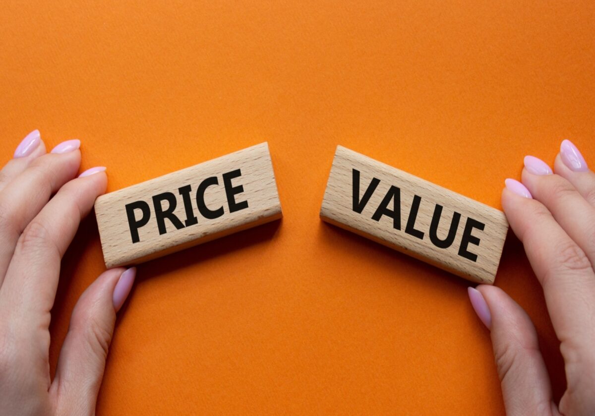 Two hands holding wooden blocks labeled "Price" and "Value" against an orange background.