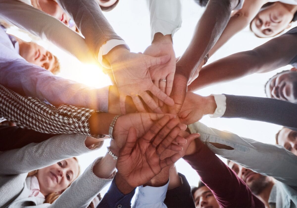 Diverse group of hands joined together representing cultural intelligence in coaching