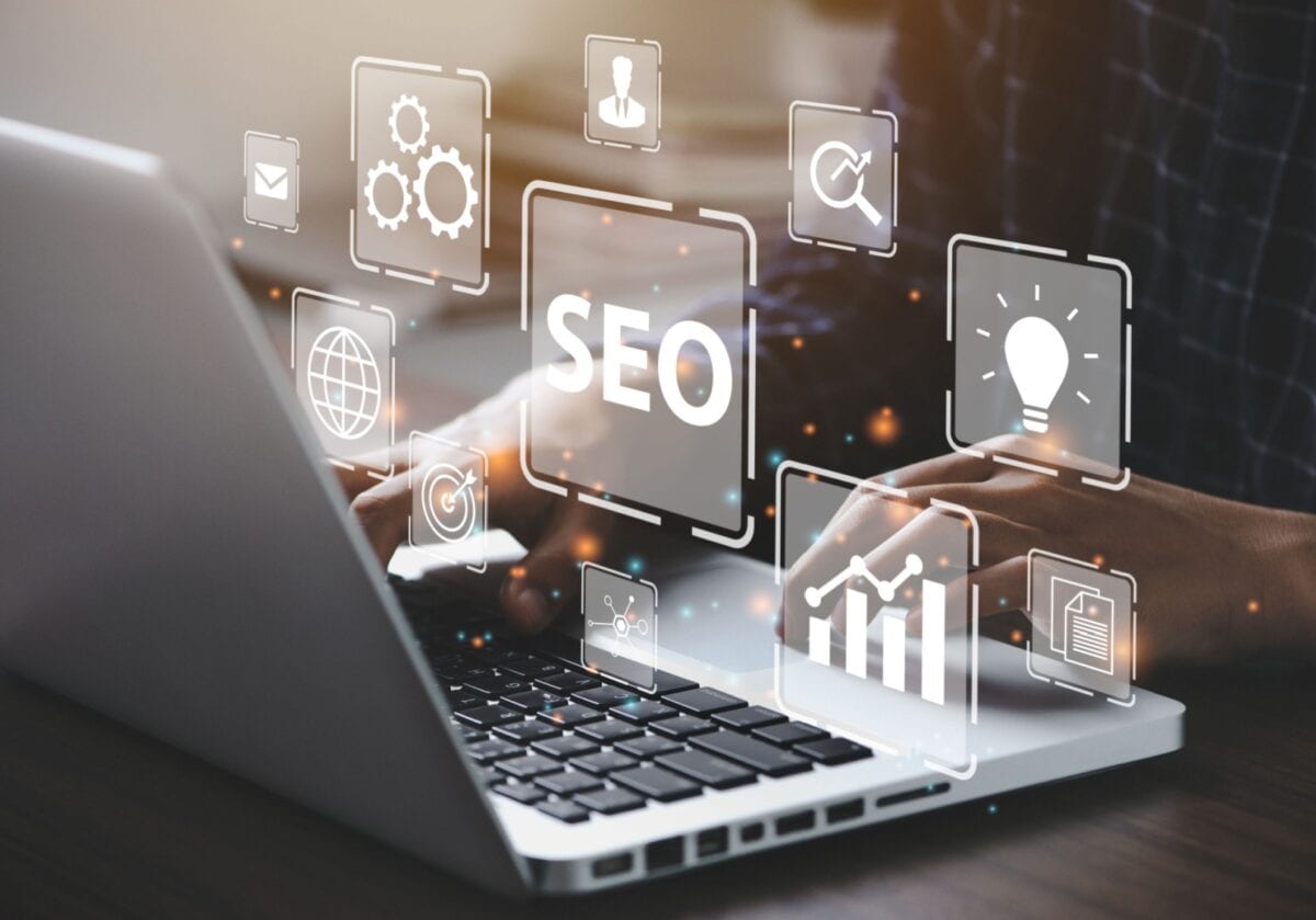 Laptop with floating SEO icons illustrating coaching website SEO strategy.