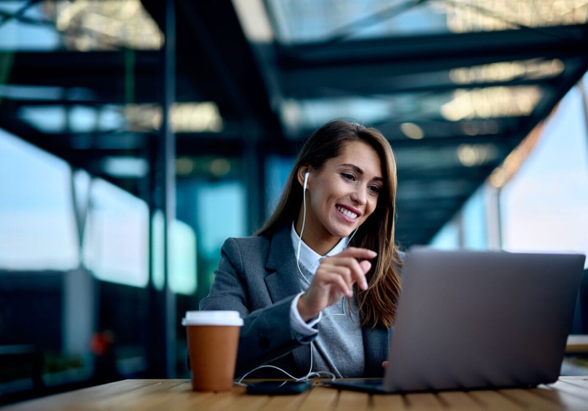 Professional smiling while engaging in an online coaching session on a laptop, representing coaching technology and the future of coaching.