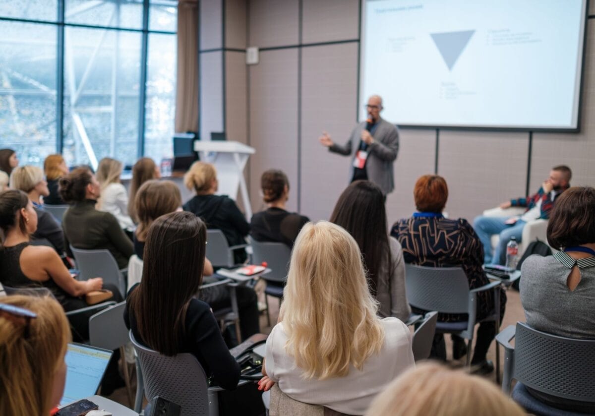A business speaker presents to an audience at a professional event.