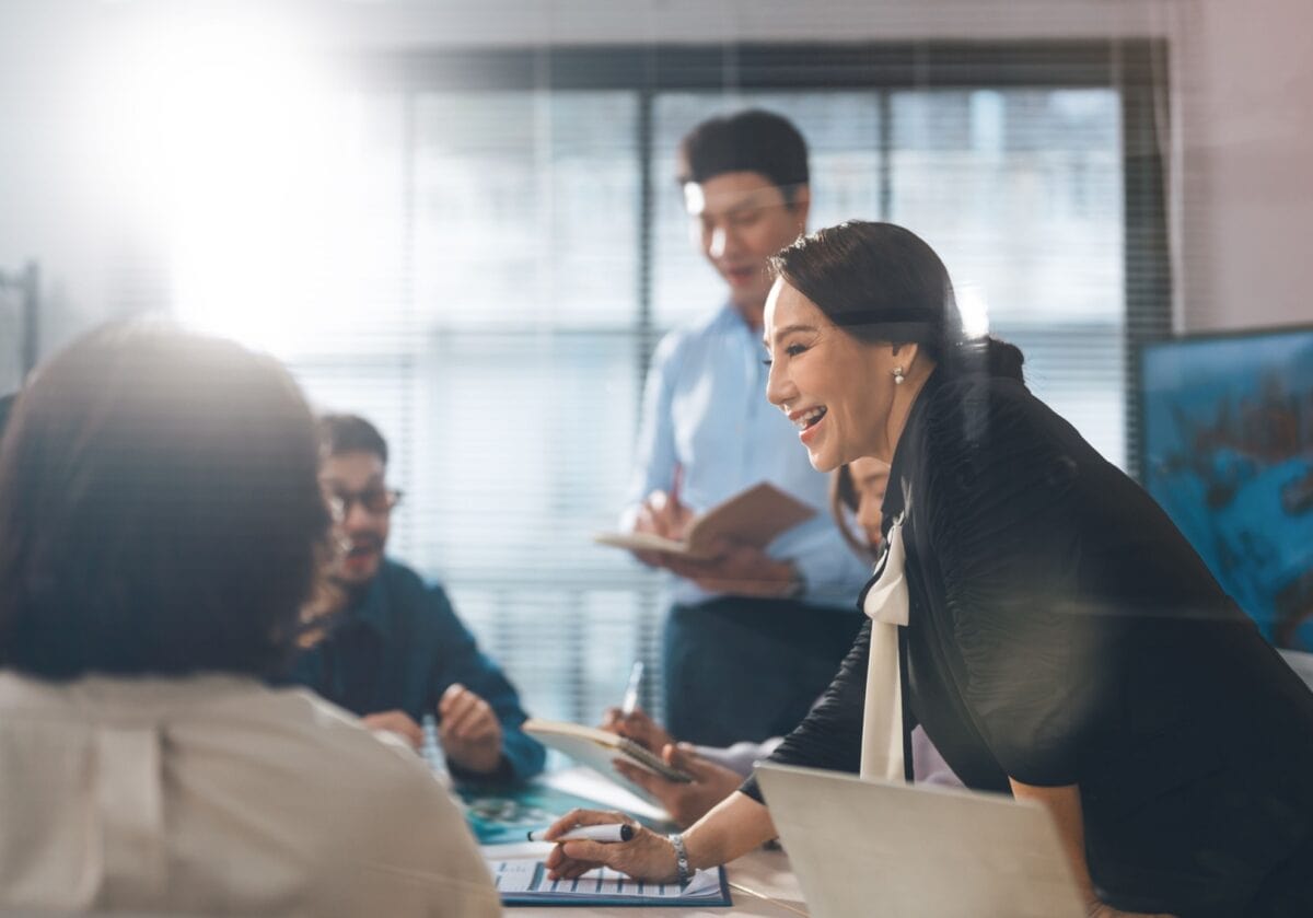 Colleagues engage in a lively discussion around a conference table during a collaborative workplace meeting.
