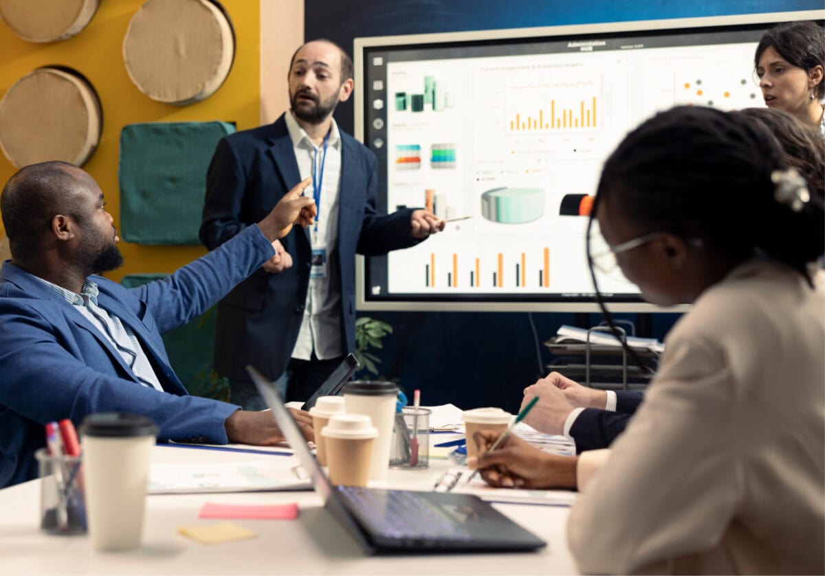 A diverse team discusses data charts during a business meeting.