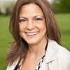 Barbara Walton headshot photo, smiling woman with brown hair wearing a light blazer and dark top outside