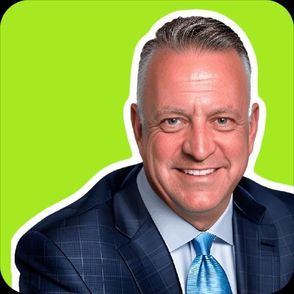 Headshot of a man in a business suit smiling in front of a green backdrop
