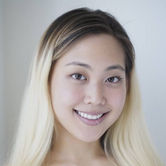 Christen Lee headshot photo, smiling blond woman in front of light gray background