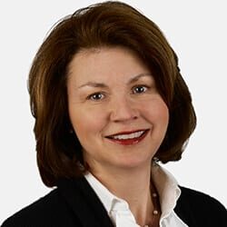 Marie Peeler PCC headshot photo, smiling woman with brown hair wearing black blazer and white collared shirt in front of white background