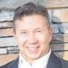 steve mitten headshot photo, smiling man in blazer in front of stone wall