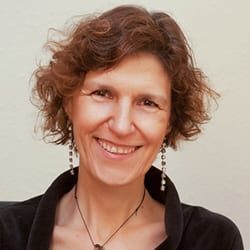 Teresa Gerreiro PCC headshot photo, smiling woman with dark top in front of a light background