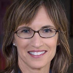Tina Mertel MCC headshot photo, smiling woman wearing glasses with brown hair