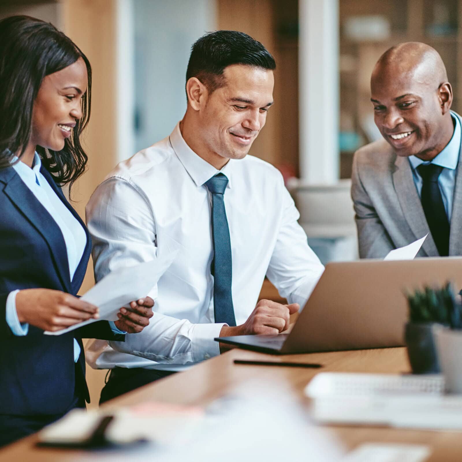 Team Coaching Three professionals — two men and a woman — are all smiling and engaged, suggesting a positive and productive team coaching session.