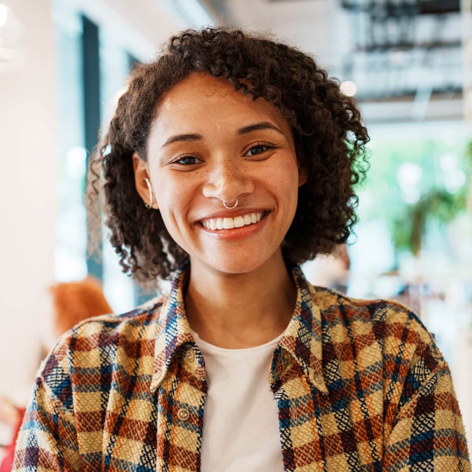 A,Smiling,Young,Woman,Is,Sitting,In,A,Stylish,Cafe