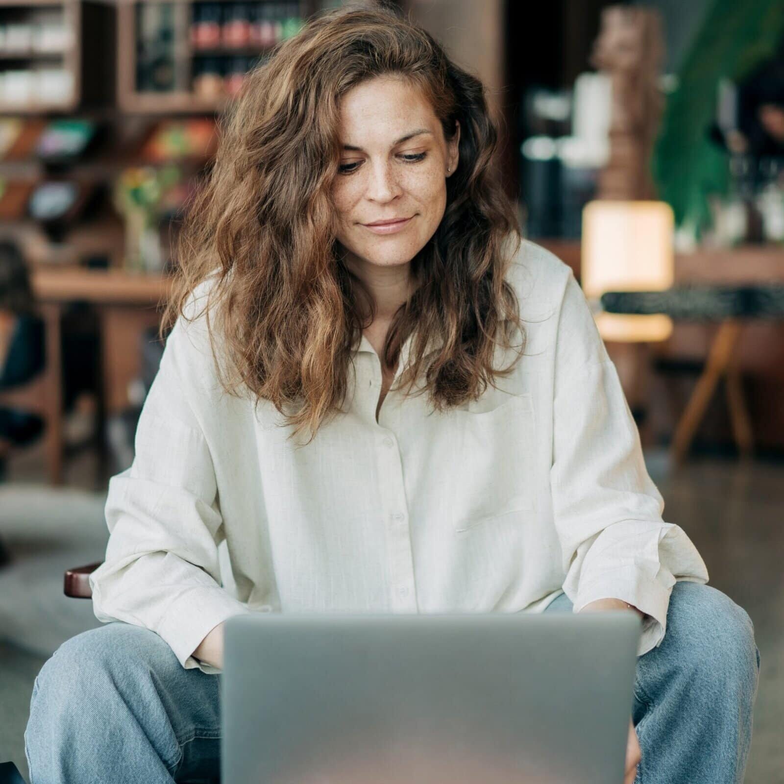 Young,Woman,Working,On,A,Laptop,In,A,Cozy,Cafe,