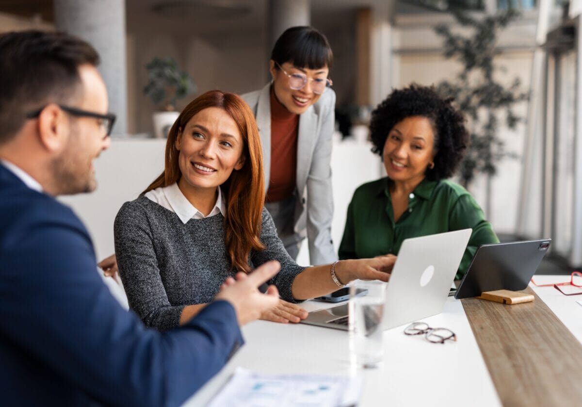 A group of professionals collaborating in a workplace, demonstrating coaching skills for leaders and a trust-based coaching culture through open conversation and active listening.