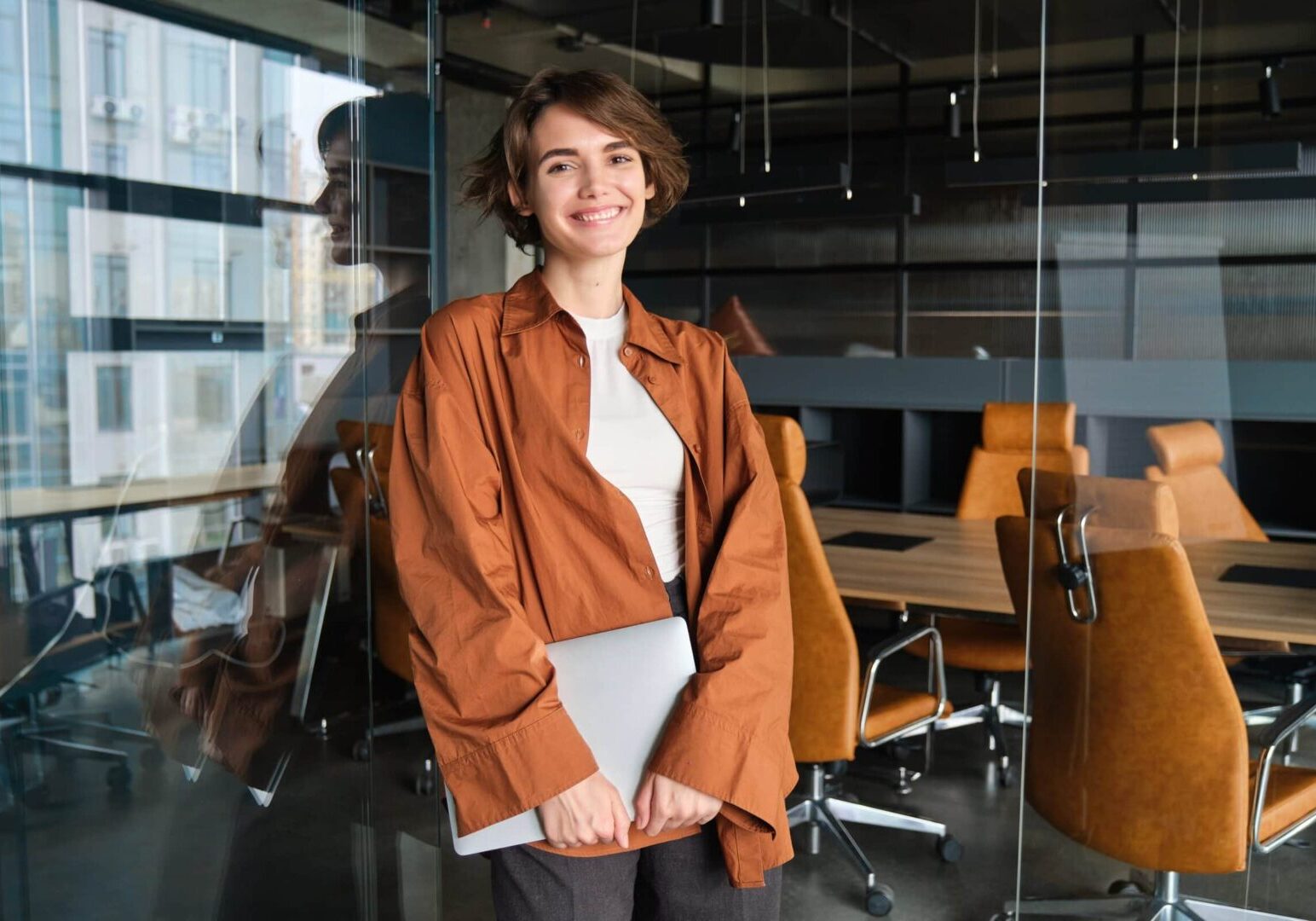 Woman holding laptop in a office looking at the camera, as she works to earn her MCS.