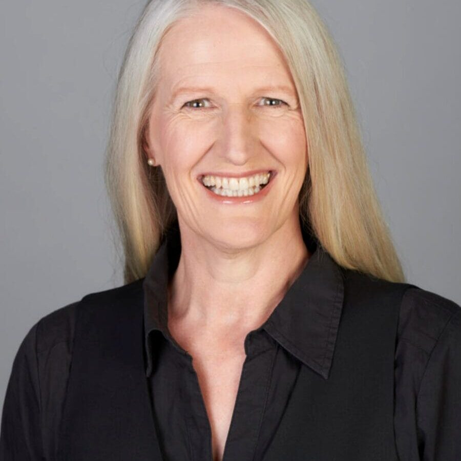 Kristen Dierolf ACTC MCC headshot photo, smiling woman with blond hair wearing black shirt in front of light gray background