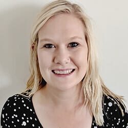 Savannah Patton headshot photo, smiling blond woman wearing black and white top in front of white wall